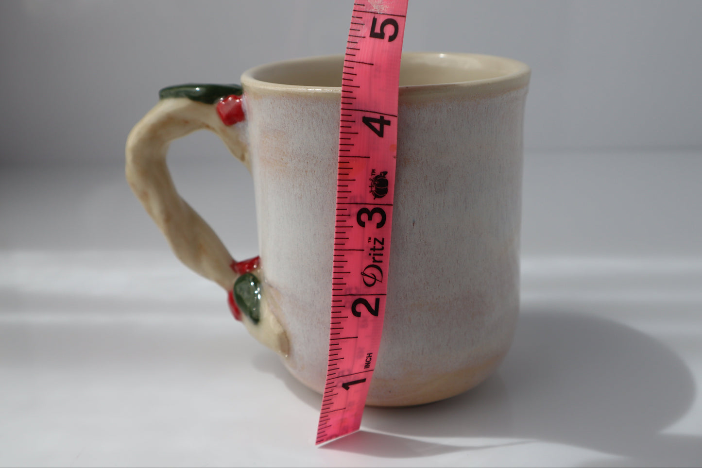Ceramic mug with a measuring tape for scale on a white background