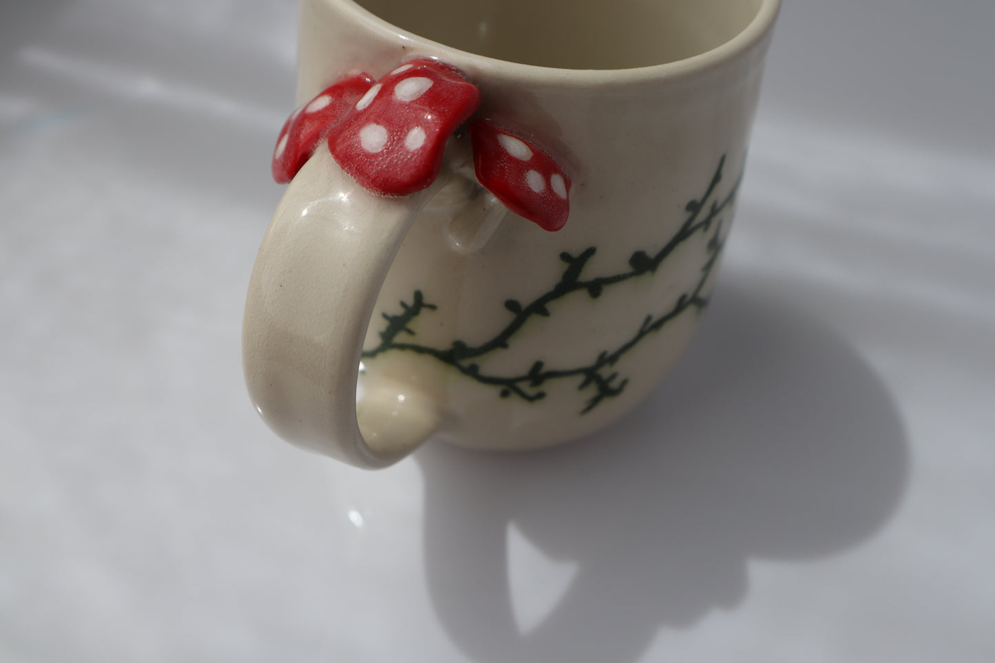 Ceramic mug with red mushrooms on the handle on a white background