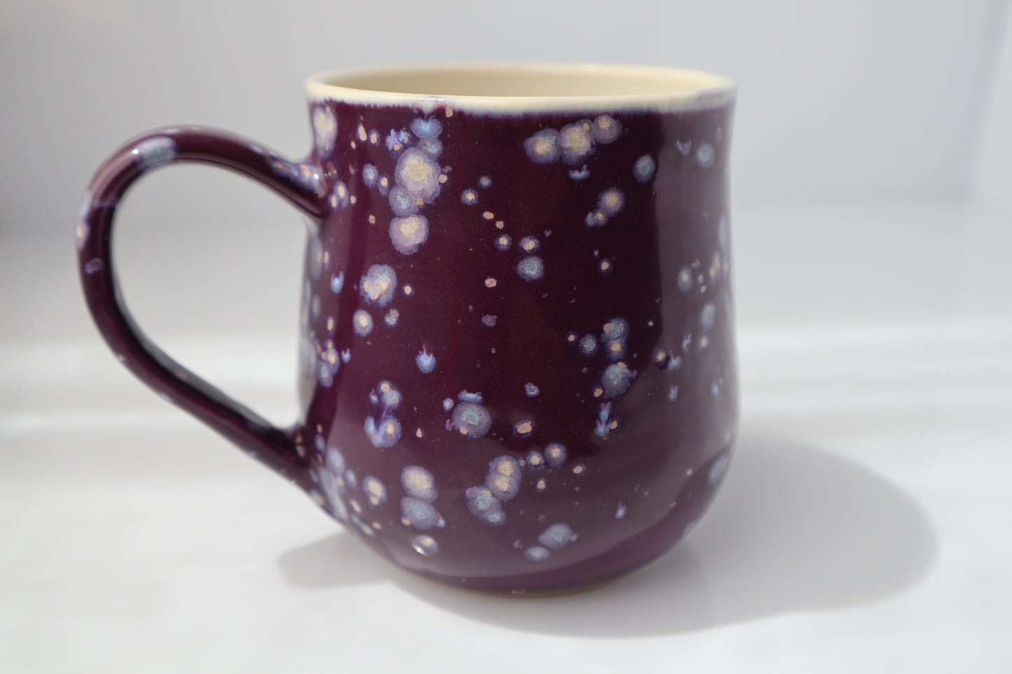 Purple mug with a speckled pattern on a white background.