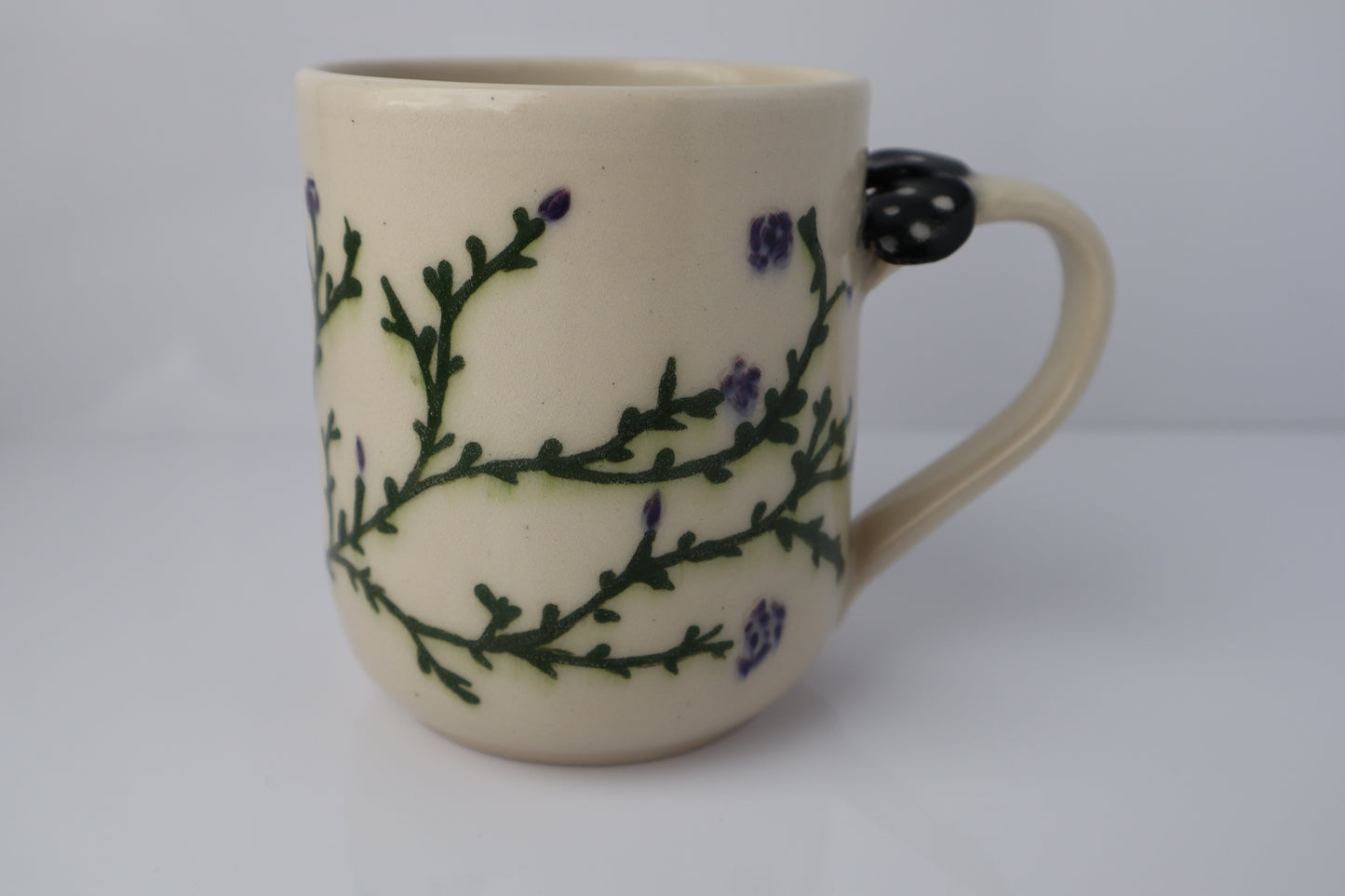 Ceramic mug with a purple floral and vine design on a white background