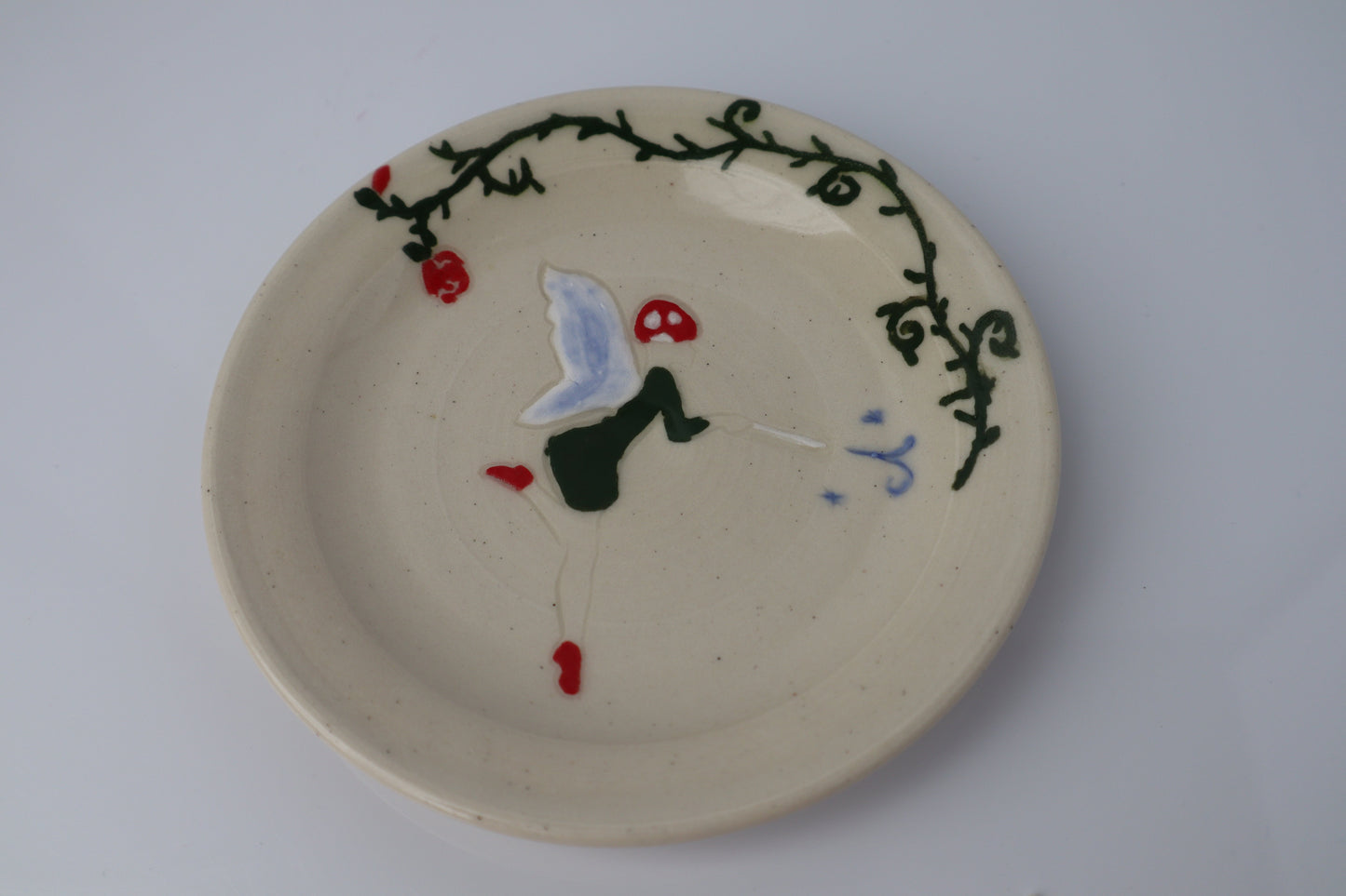 Ceramic plate with fairy on a plain background