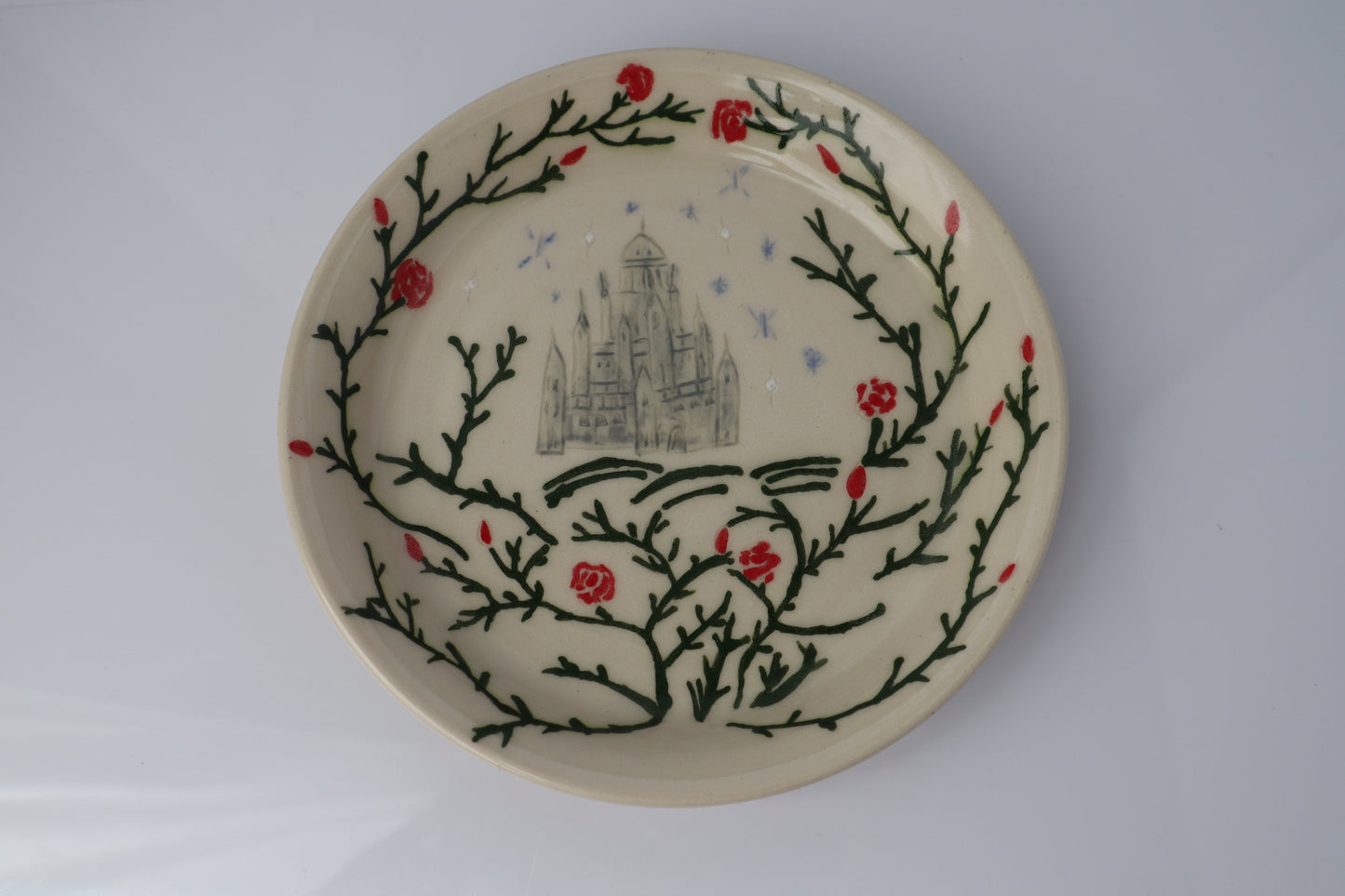 Ceramic plate with decorative design of branches and flowers on a white background