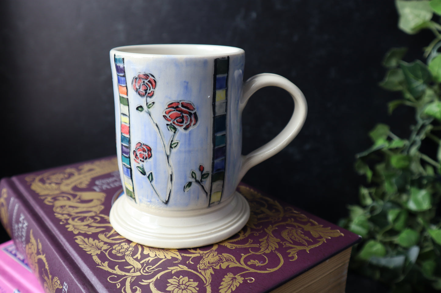 Decorative mug with floral rose design on a  book with gold patterns