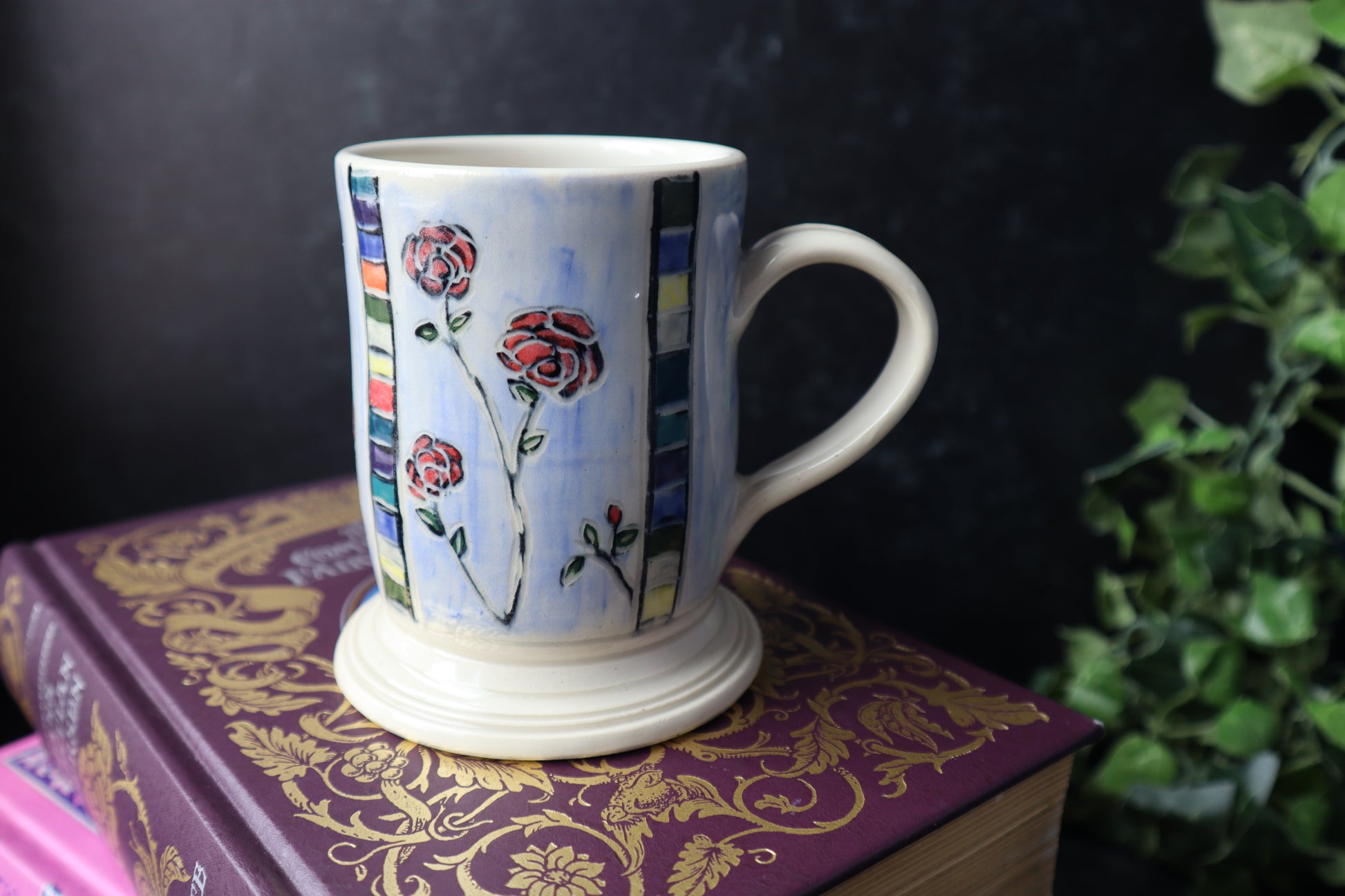 Decorative mug with floral rose design on a  book with gold patterns