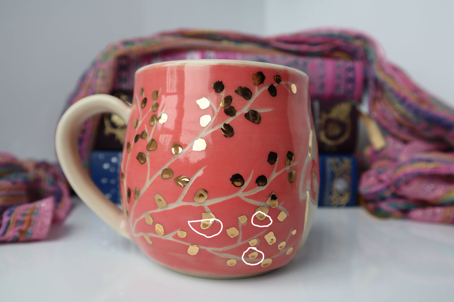 Pink mug with gold patterns with colorful fabric in the background