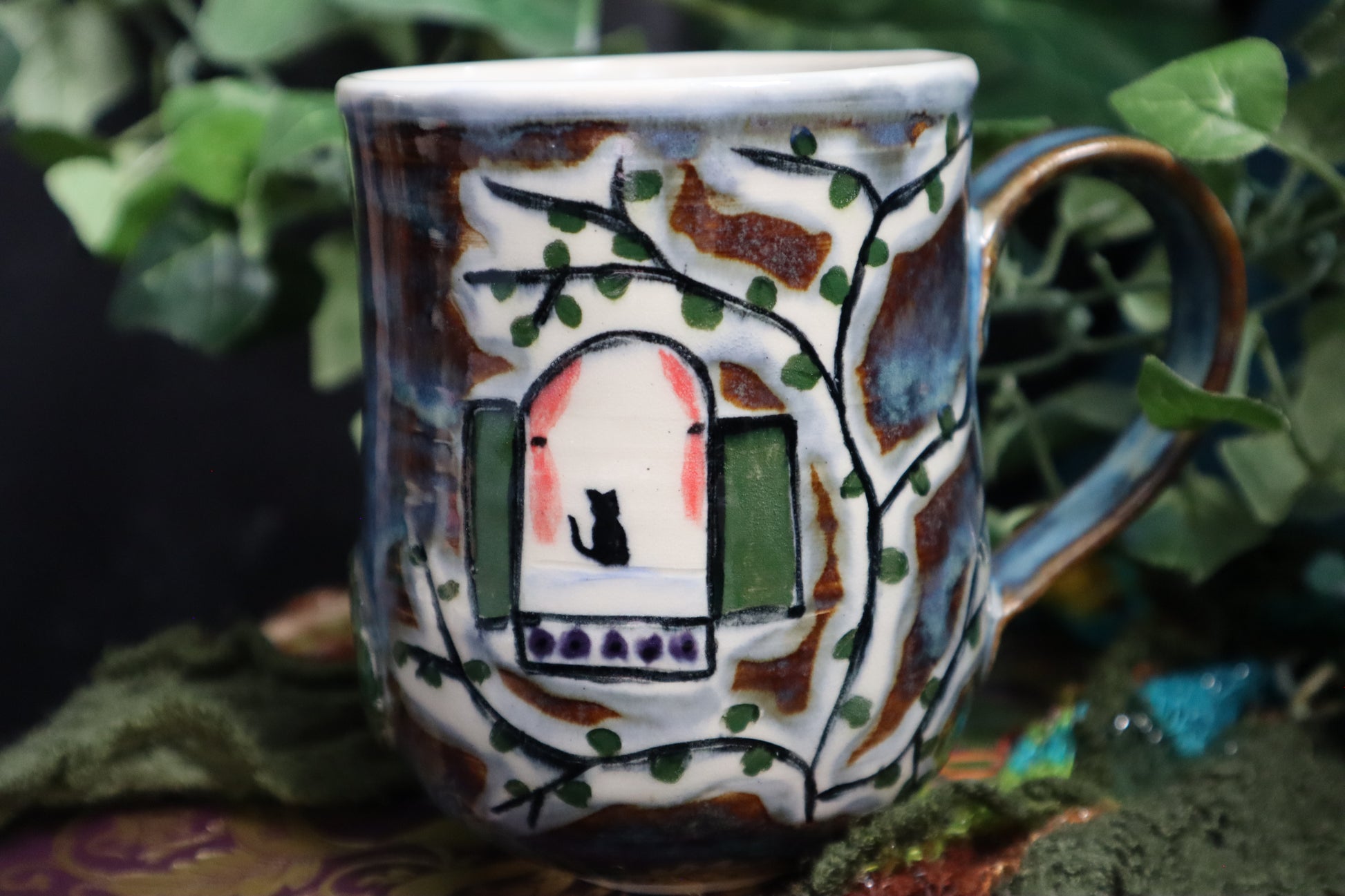 Ceramic mug with artistic design of a house and tree on a natural background