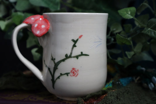 Green vines and mushroom on a white mug with foliage  as a backdrop