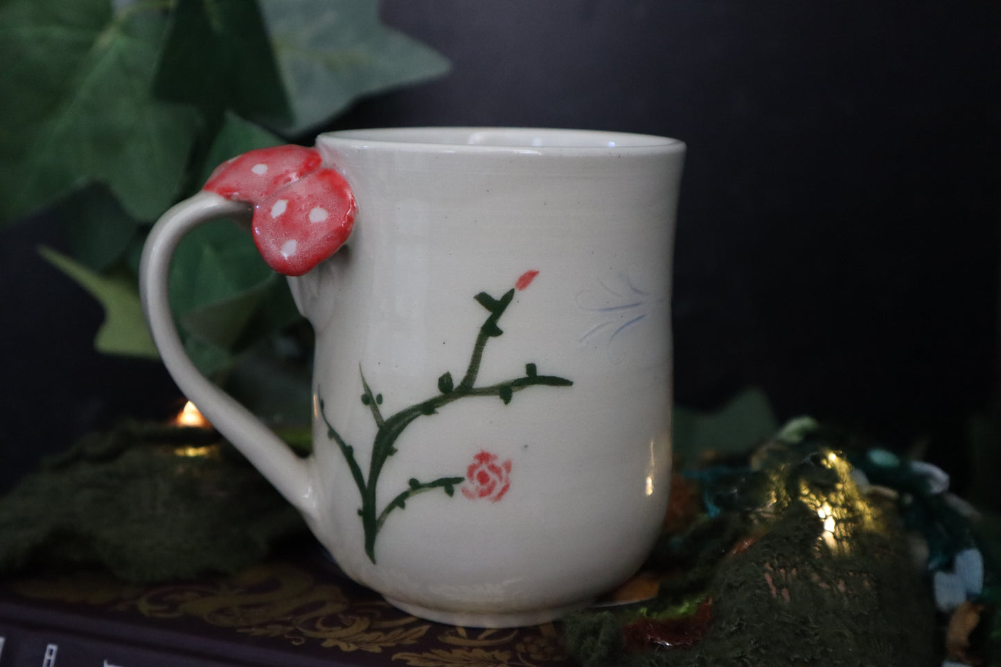 Green vines and mushroom on a white mug with foliage  as a backdrop