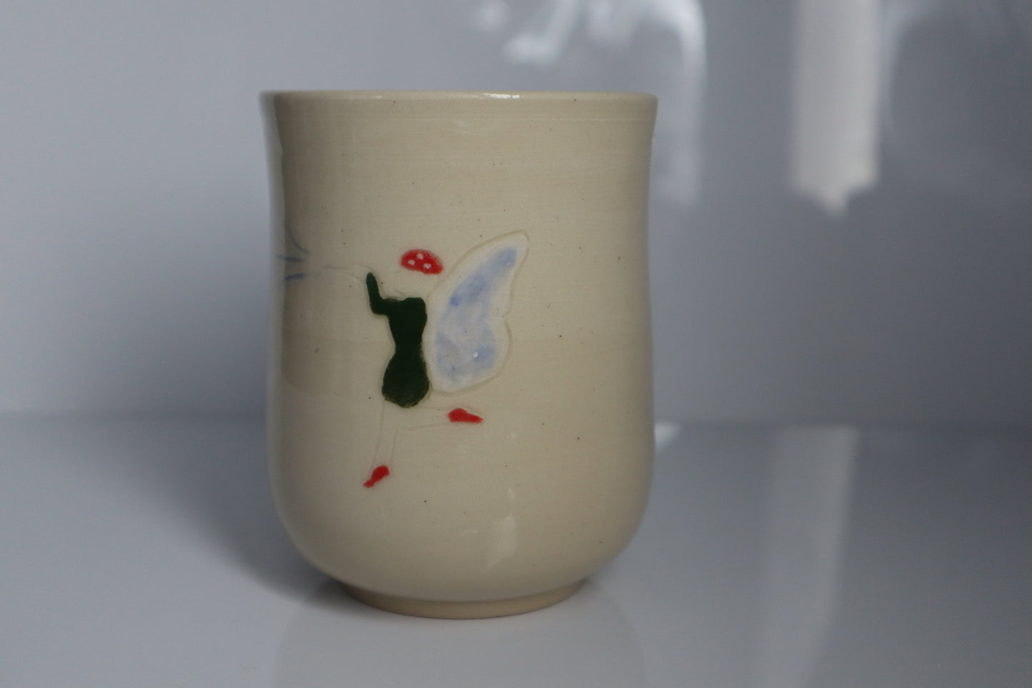 Fairy wearing a mushroom cap on a white mug with a white backdrop
