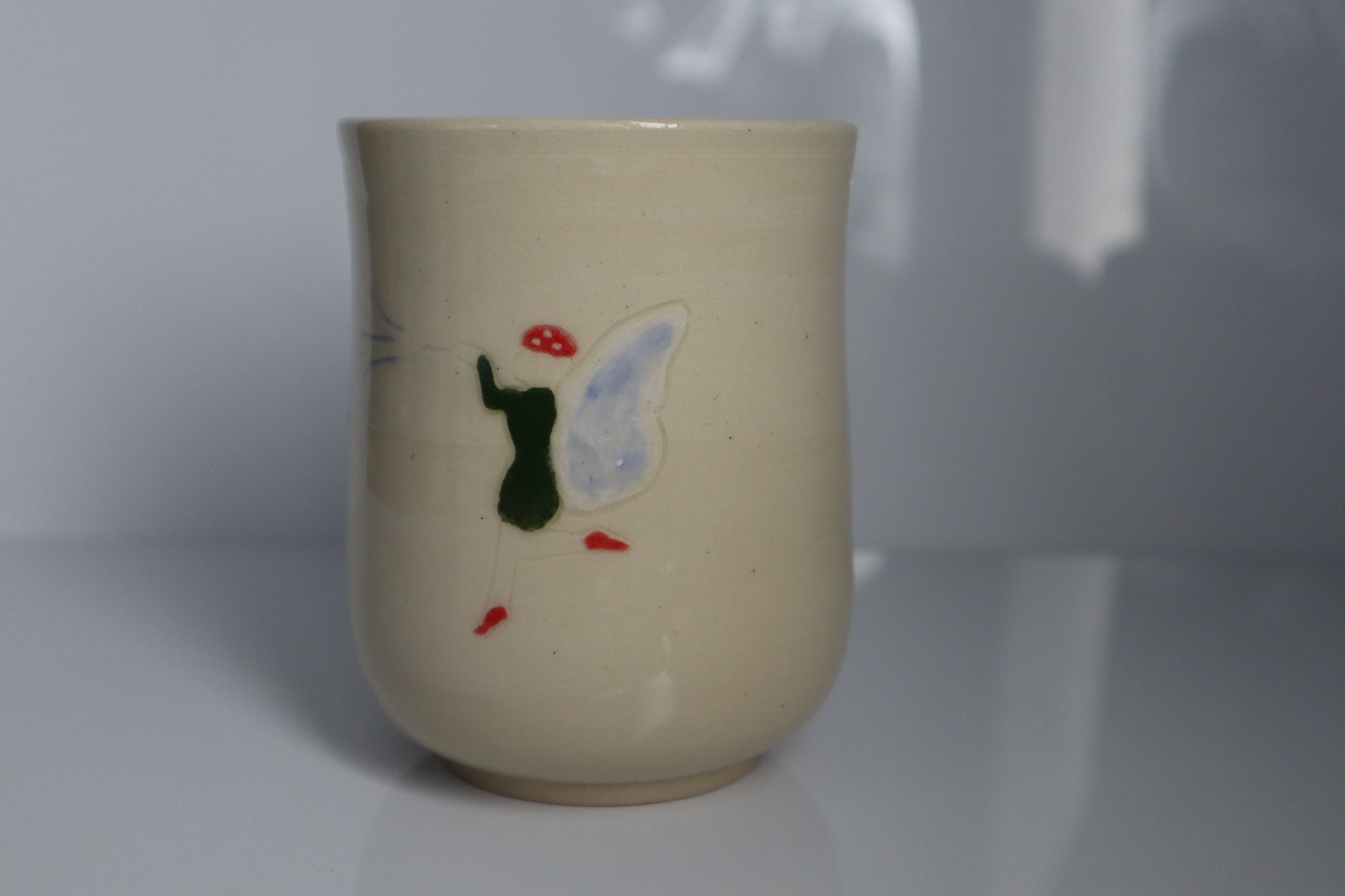 Fairy wearing a mushroom cap on a white mug with a white backdrop