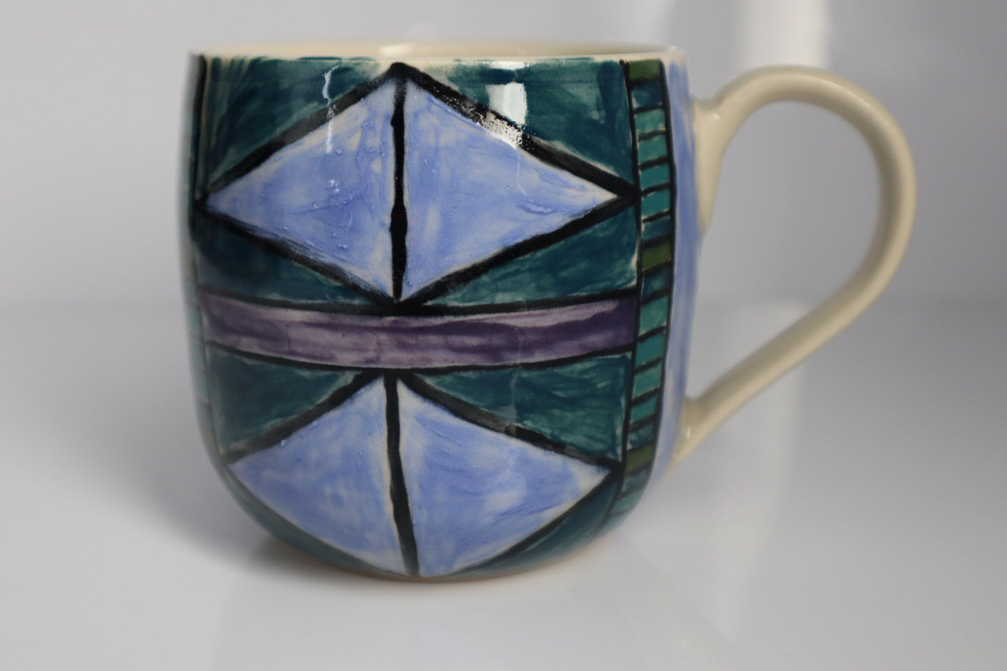 Ceramic mug with geometric blue and green design on a white background