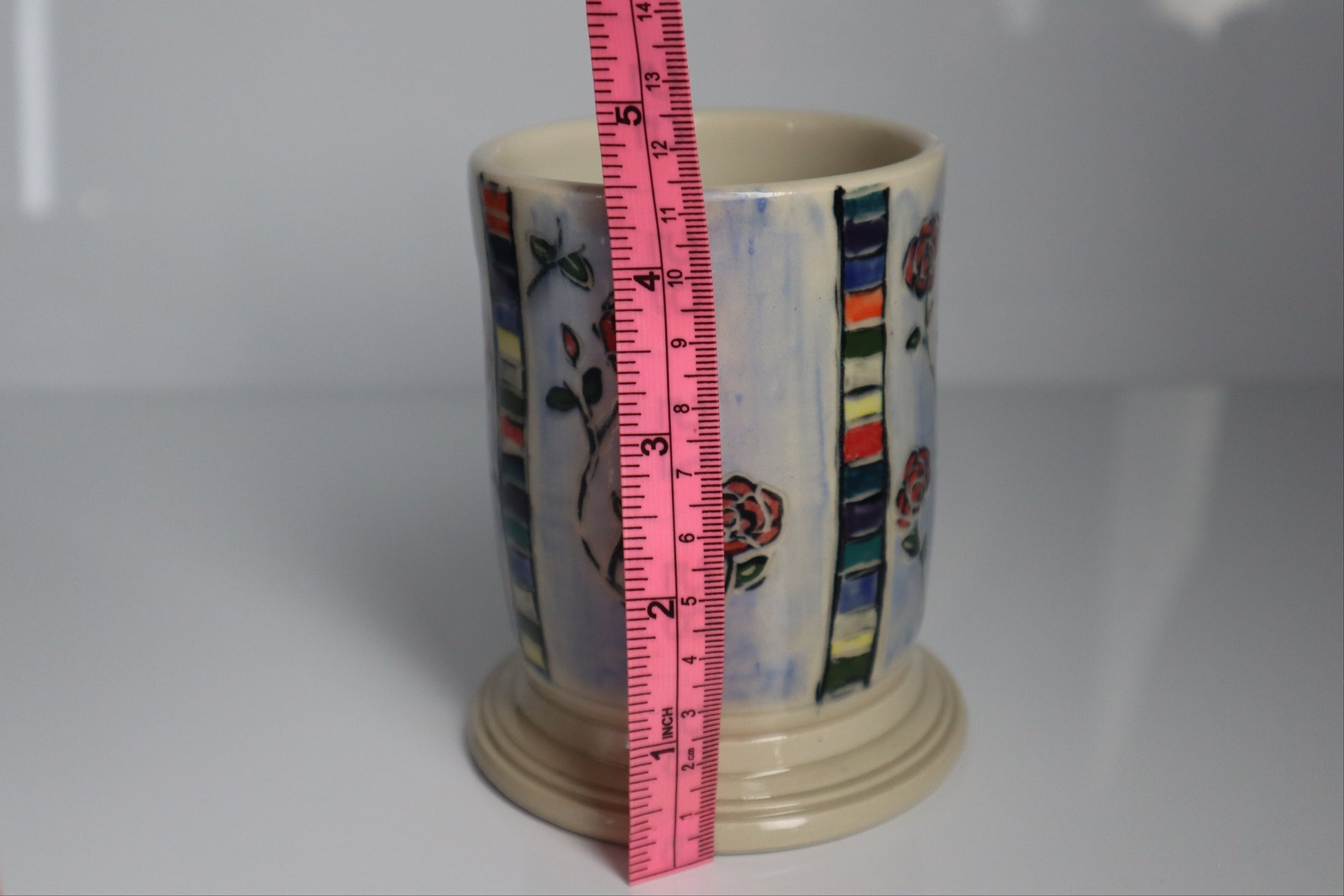 Ceramic mug with a measuring tape for scale on a white background