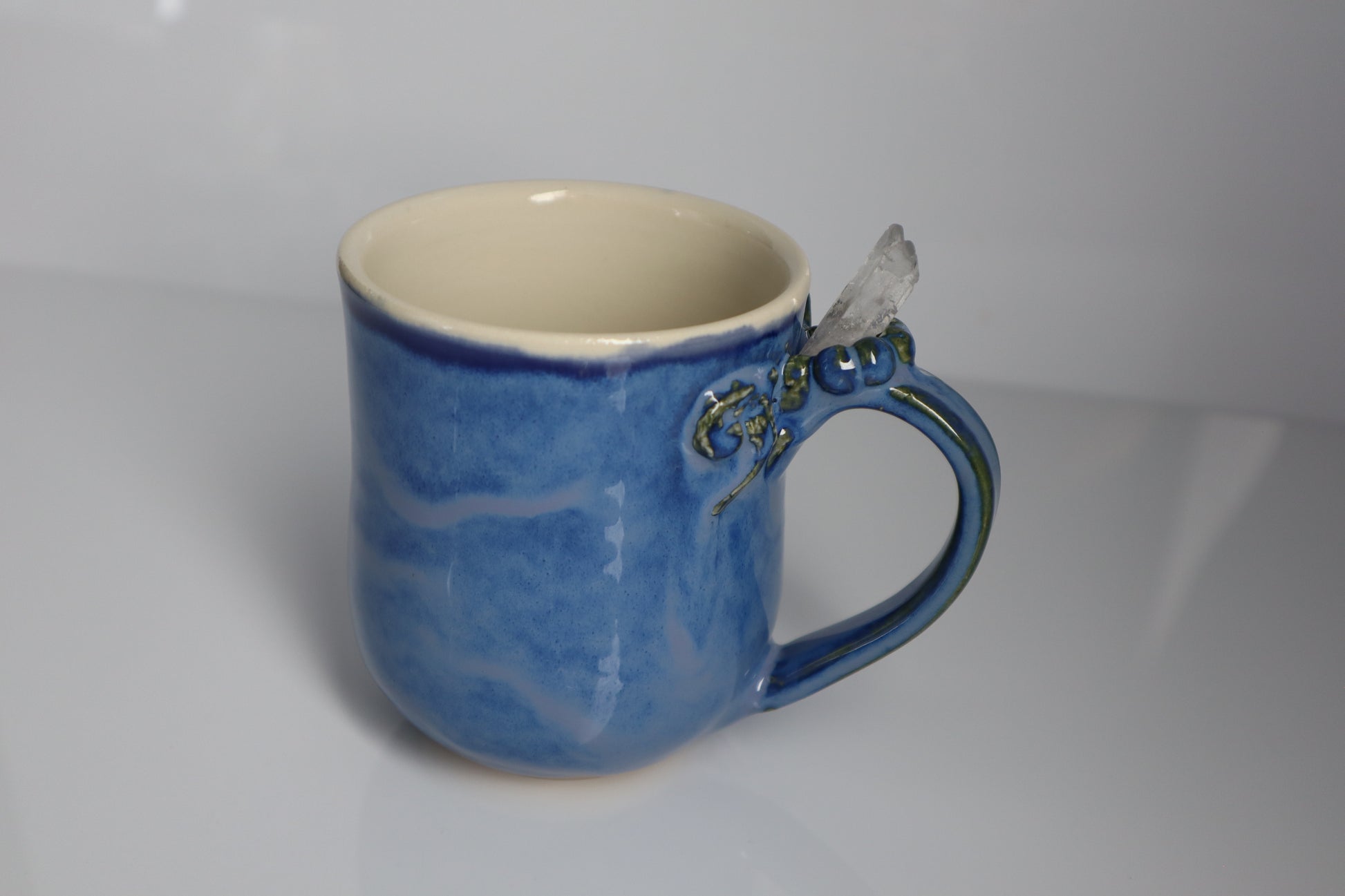 Blue ceramic mug with a crystal handle on a white background