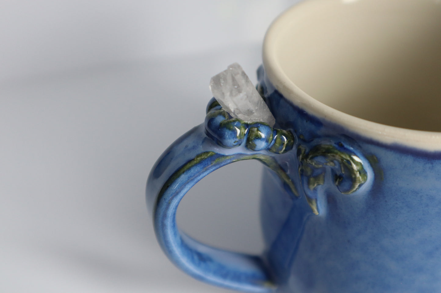 Close-up of a blue ceramic mug with decorative handle on a white background