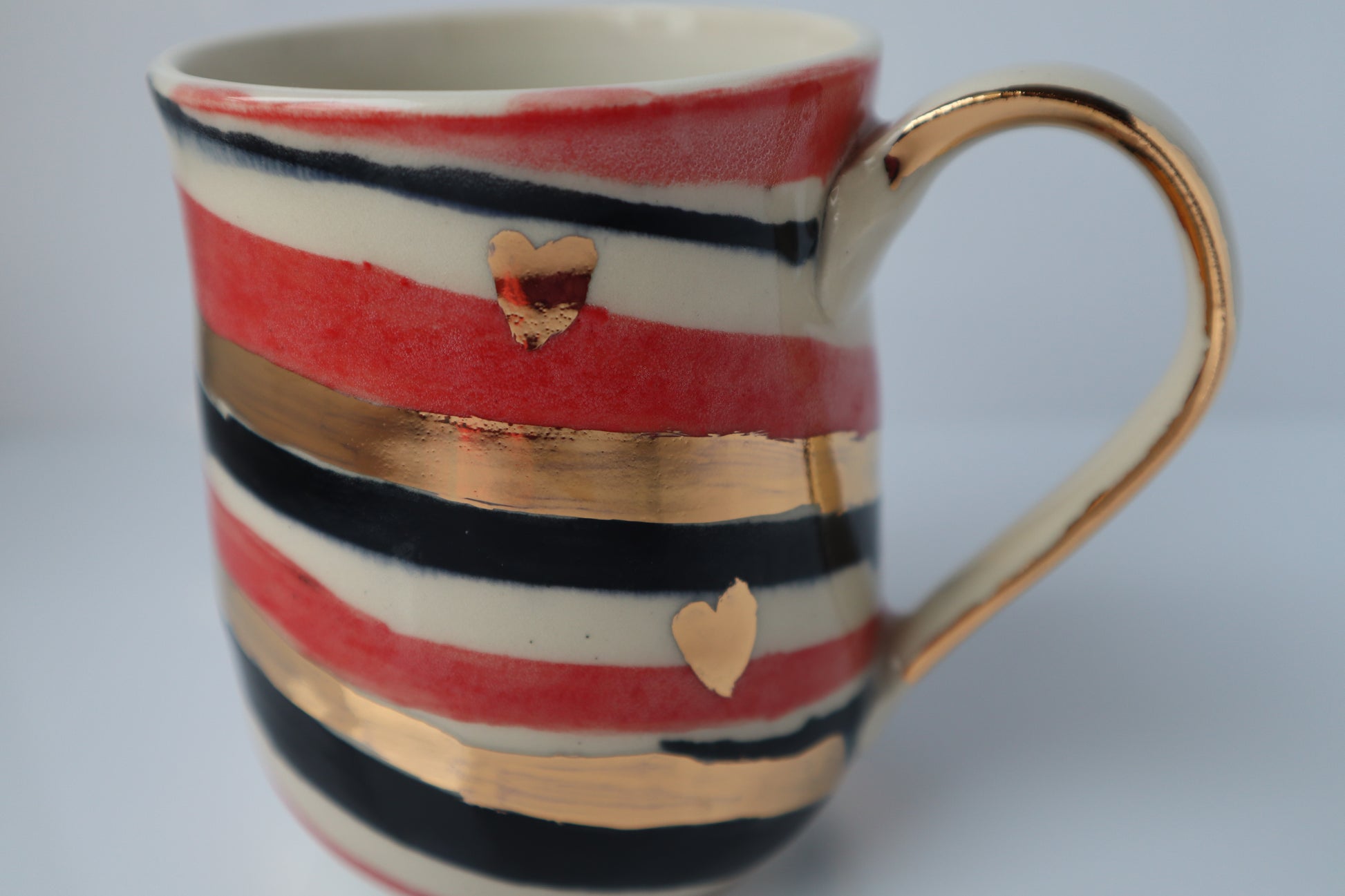 Striped mug with gold hearts on a white background