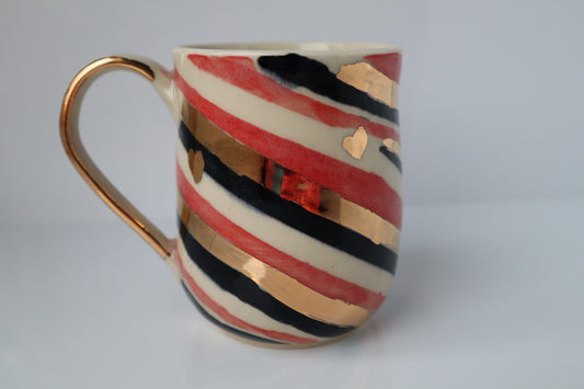 Colorful striped mug with gold accents on a white background