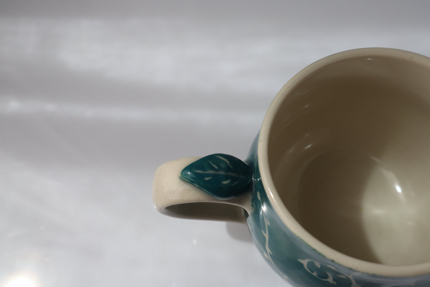 Ceramic mug with a leaf-shaped handle on a white background