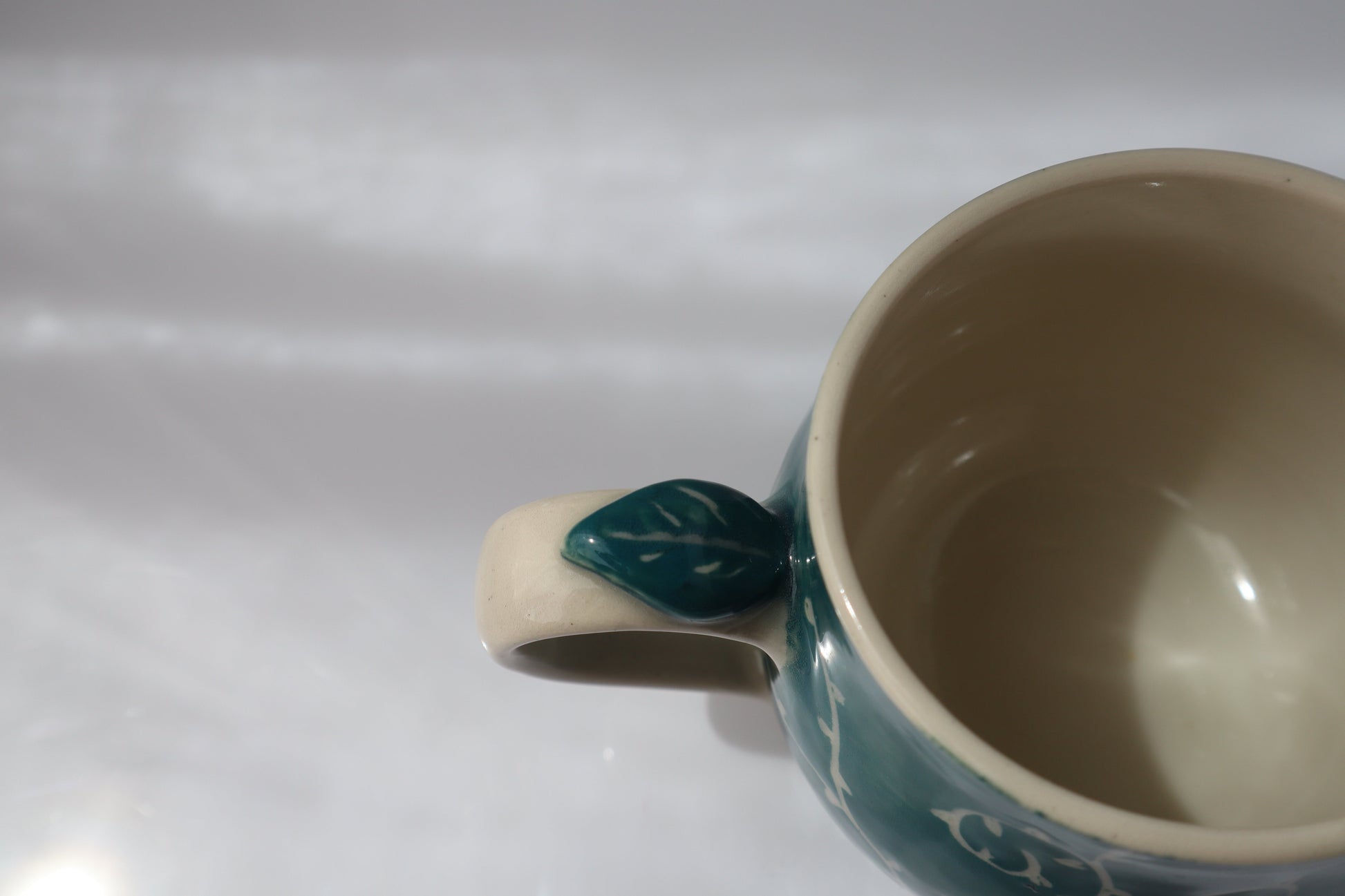 Ceramic mug with a leaf-shaped handle on a white background