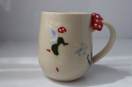 Ceramic mug with fairy and mushroom designs on a white background