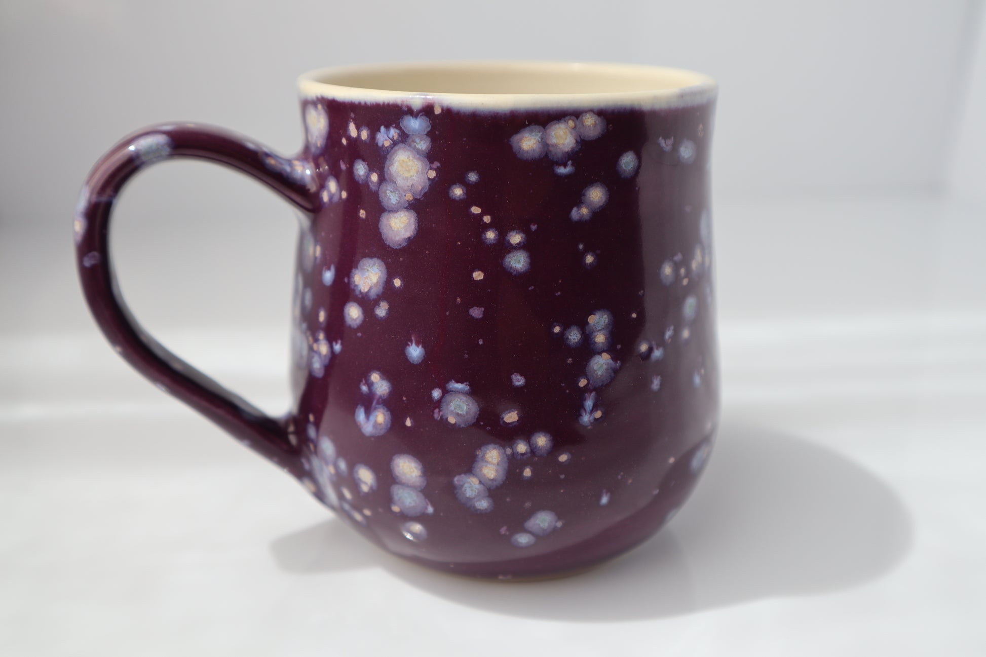 Purple mug with a speckled pattern on a white background.