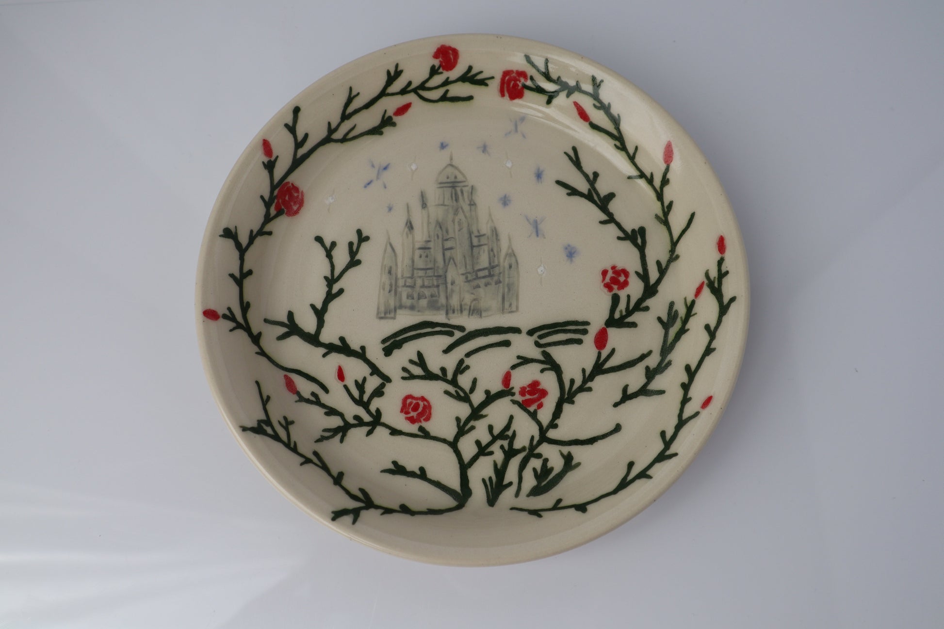 Ceramic plate with decorative design of branches and flowers on a white background