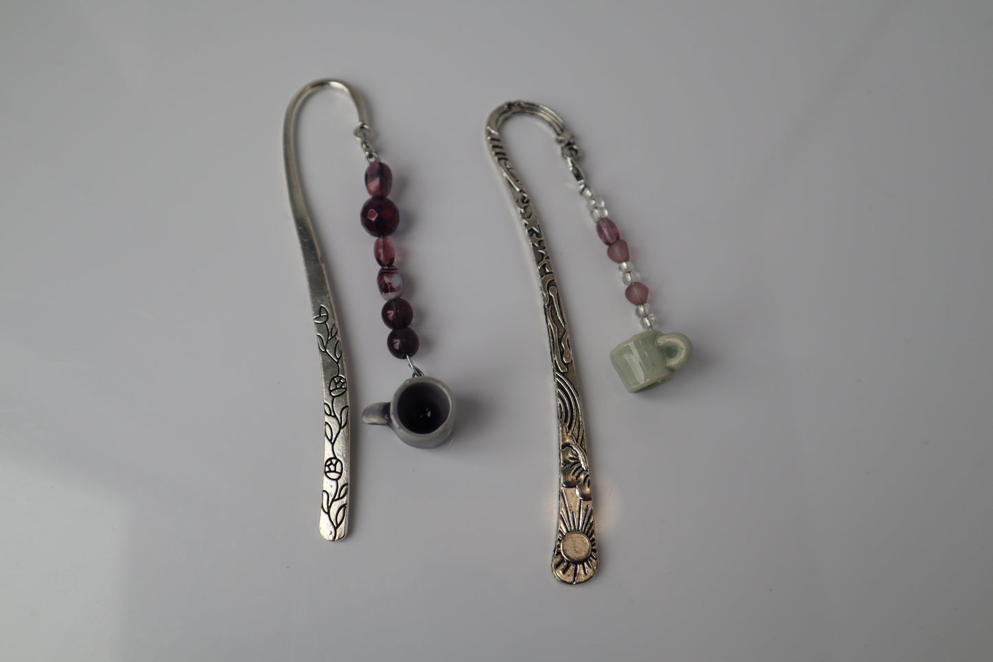 Two decorative bookmarks with beads and small pottery on a gray background