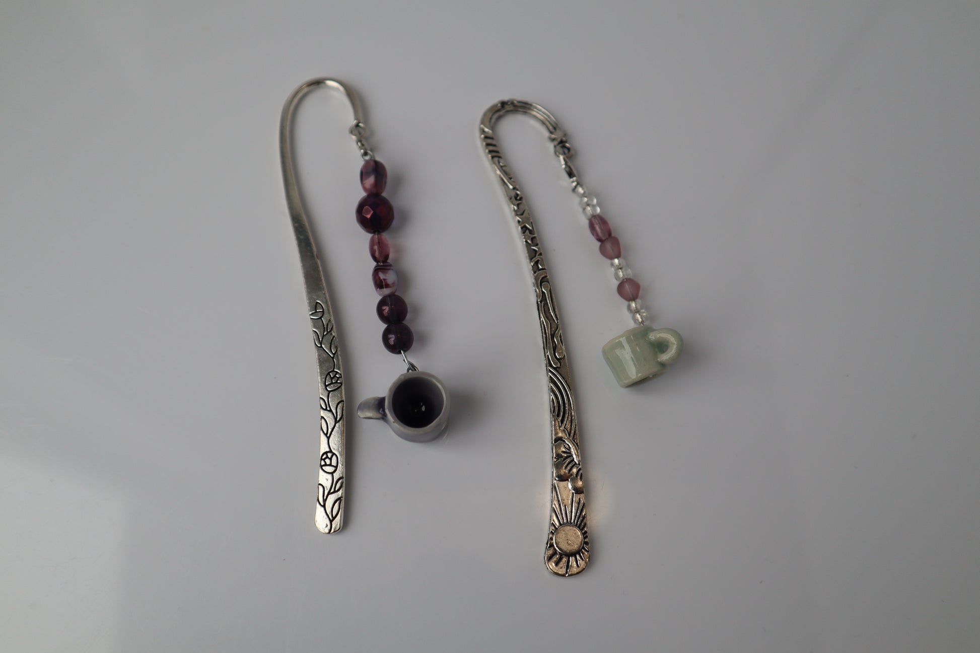 Two decorative bookmarks with beads and small pottery on a gray background