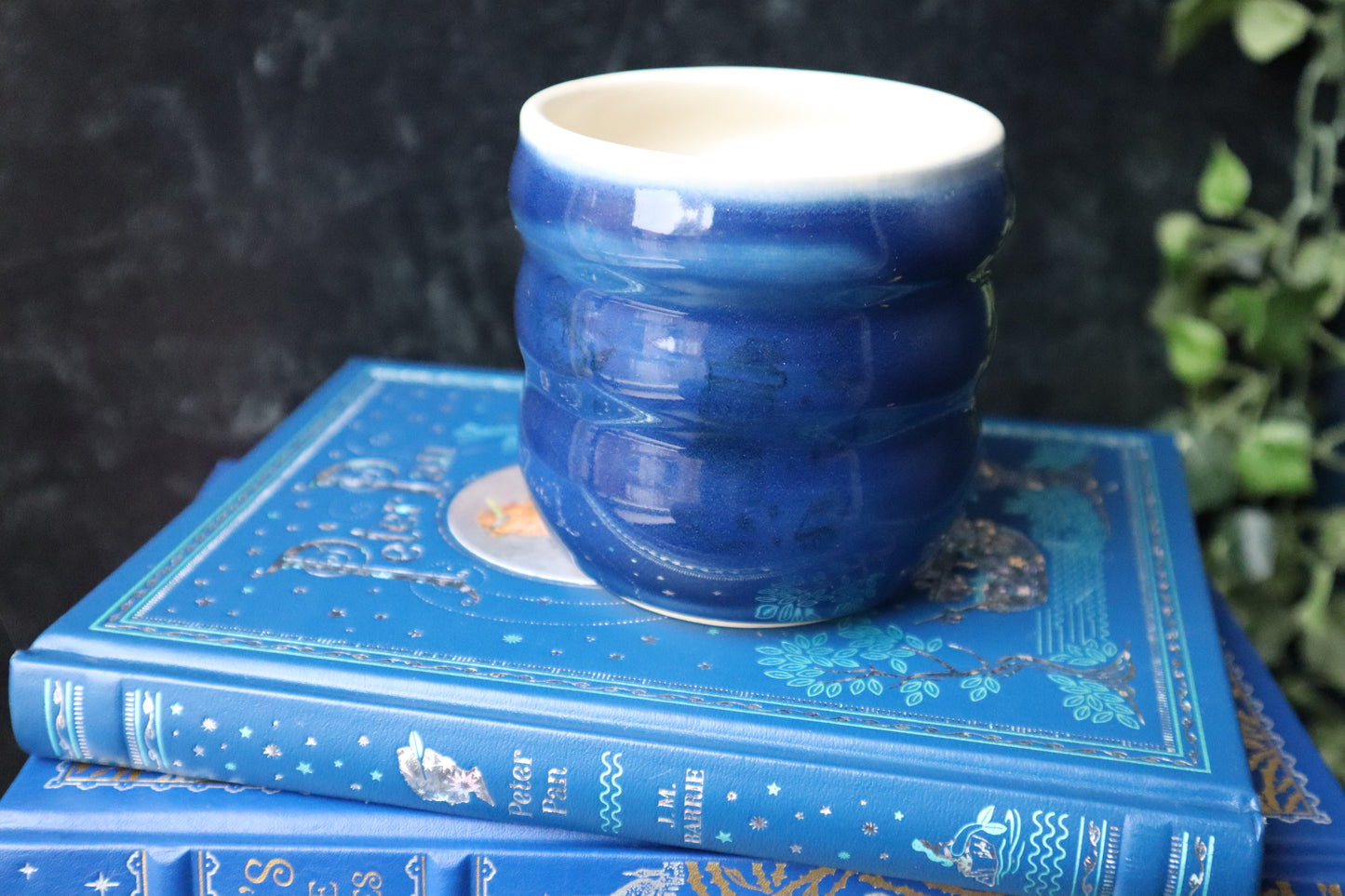 Blue ceramic cup on a stack of books with a black background